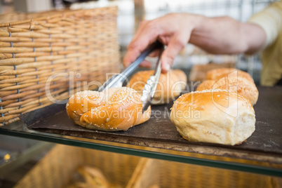 Hand of server taking bread with tongs