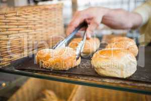 Hand of server taking bread with tongs