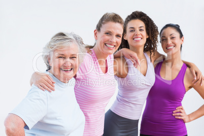 Happy friends standing arms around in fitness studio