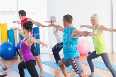 People doing warrior pose in yoga class