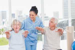 Trainer assisting senior couple to exercise