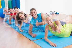 People on exercise mats gesturing thumbs up at gym