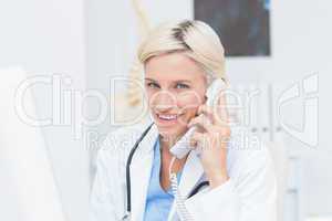 Female doctor using land line phone in clinic