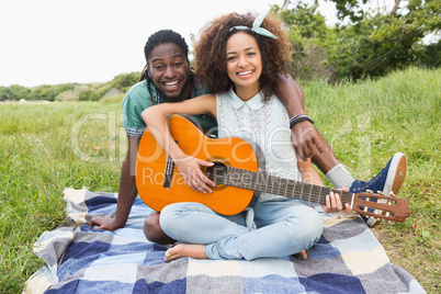 Young couple on a picnic playing guitar