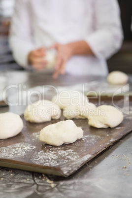 Baker kneading uncooked dough on worktop
