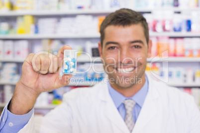 Handsome pharmacist showing medicine jar