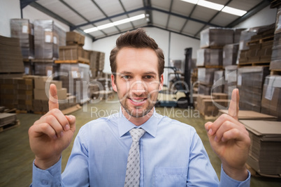 Smiling warehouse manager pointing up with finger