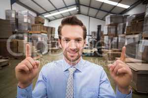 Smiling warehouse manager pointing up with finger