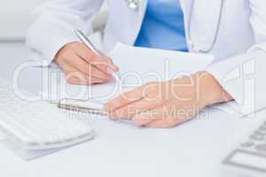 Female doctor writing prescriptions at table