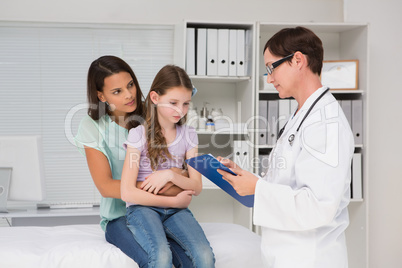 Doctor examining little girl with her mother