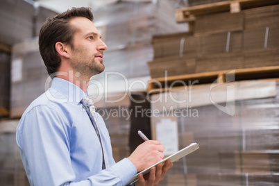 Serious warehouse manager checking inventory