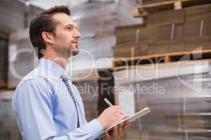 Serious warehouse manager checking inventory