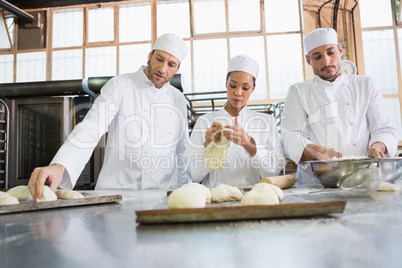 Concentrated colleagues kneading uncooked dough