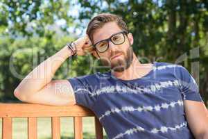 Handsome hipster sitting on park bench