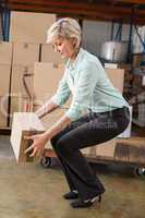 Warehouse manager picking up cardboard box