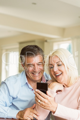 Happy mature couple looking at smartphone together