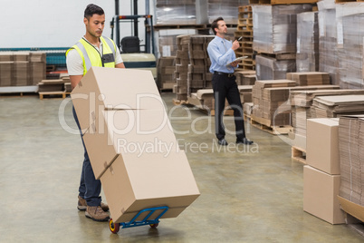 Warehouse worker moving boxes on trolley