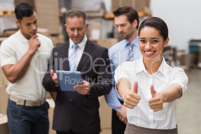 Manager showing thumbs up in front of her colleagues