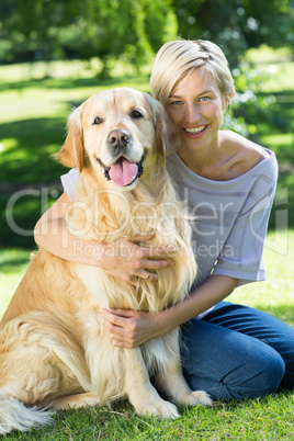 Happy blonde hugging her dog in the park