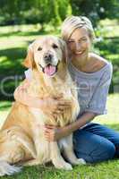 Happy blonde hugging her dog in the park