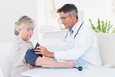 Doctor tying blood pressure belt on female patients hand