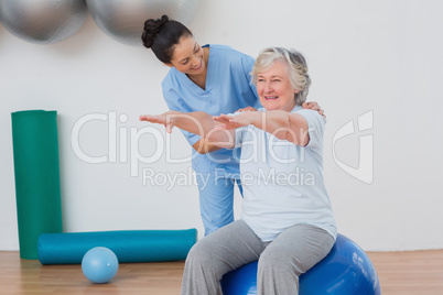 Instructor assisting senior woman in exercising