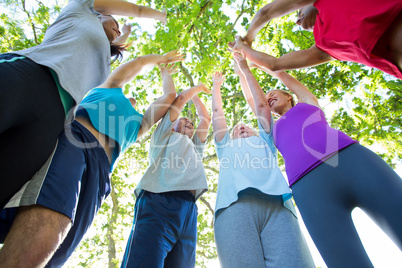 Happy athletic group putting up their hands together