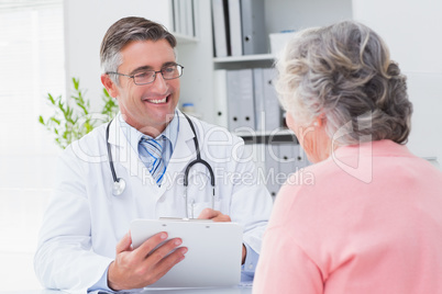 Smiling doctor writing prescriptions for patient
