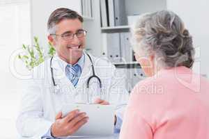 Smiling doctor writing prescriptions for patient