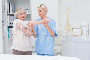 Nurse assisting senior patient in raising arm