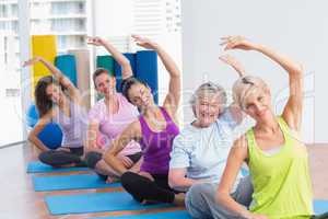 Women practicing stretching exercise in gym class
