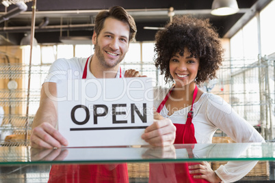 Smiling team posing behind the counter with open sign