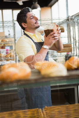 Smiling waiter smelling bread freshly baked