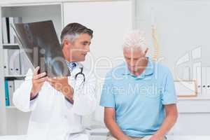 Doctor explaining x-ray while looking at sad senior patient