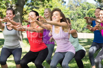 Fitness group squatting in park