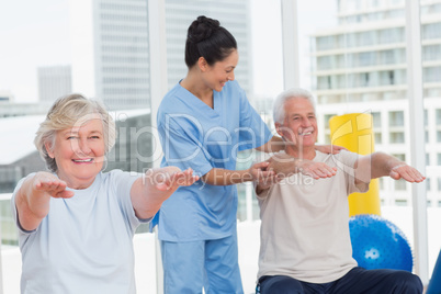 Trainer assisting senior couple in exercising