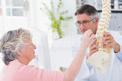 Patient looking at anatomical spine while doctor explaing her