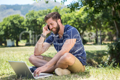 Handsome hipster using laptop in park