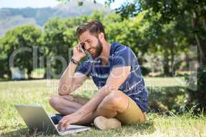 Handsome hipster using laptop in park