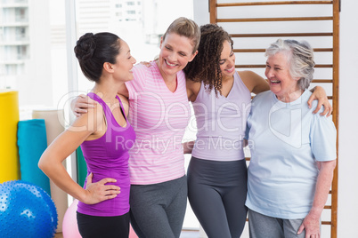 Female friends standing arms around in gym