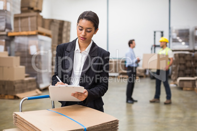 Pretty warehouse manager writing on clipboard