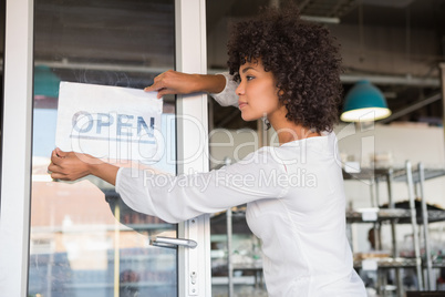 Pretty worker putting up a open sign