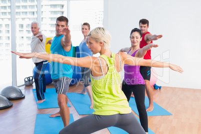 People practicing warrior pose in fitness club