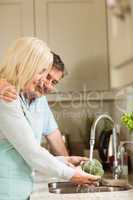 Happy mature couple washing broccoli