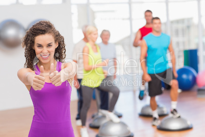 Happy woman gesturing thumbs up at gym