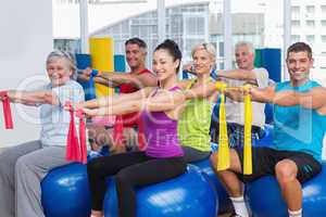 Happy people exercising with resistance bands in gym
