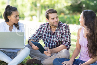 Smiling friends using media devices in park