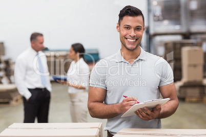 Manager looking at camera while holding clipboard