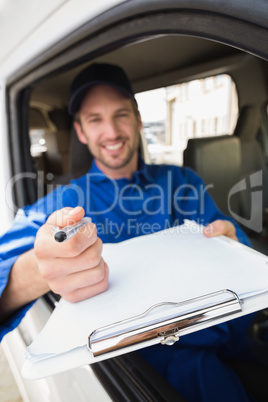 Happy delivery man showing clipboard to sign to customer