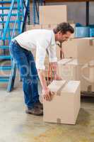 Warehouse manager picking up cardboard box